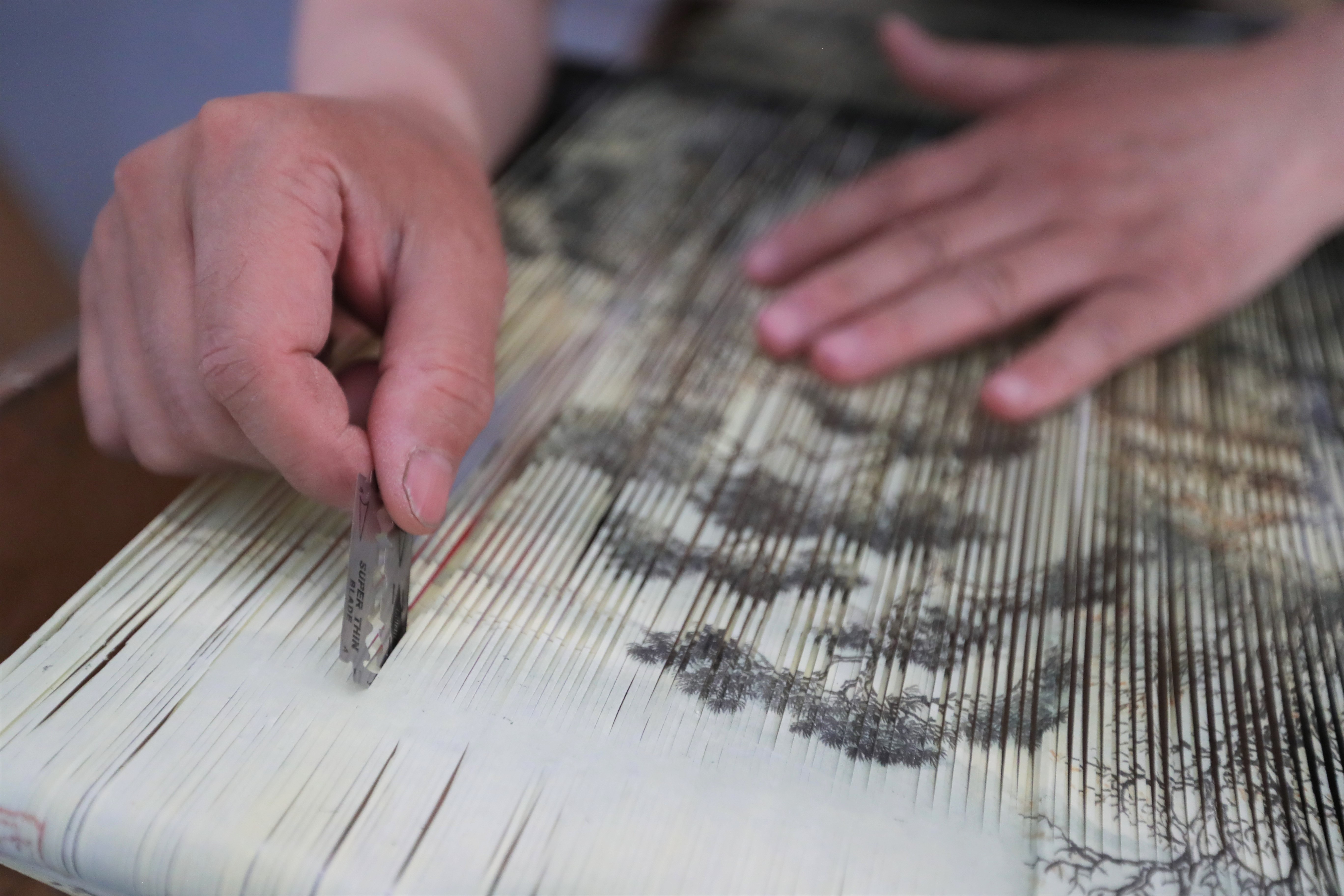7月8日,在庄浪县泥金纸织画传习所,魏巍在裁切国画,制作泥金纸织画的"