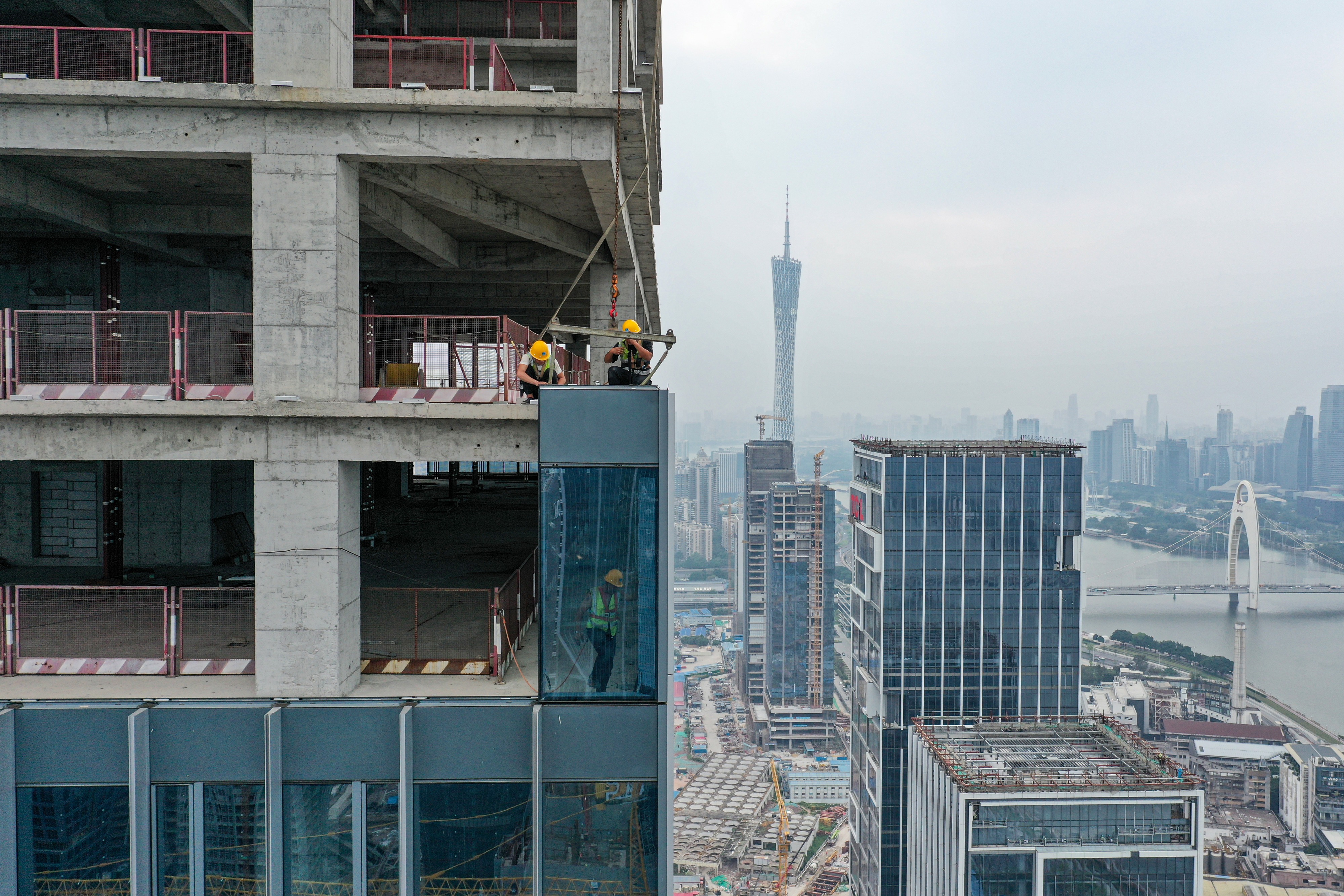 苏亮亮(上左)与工友进行单元体幕墙板块吊装作业.