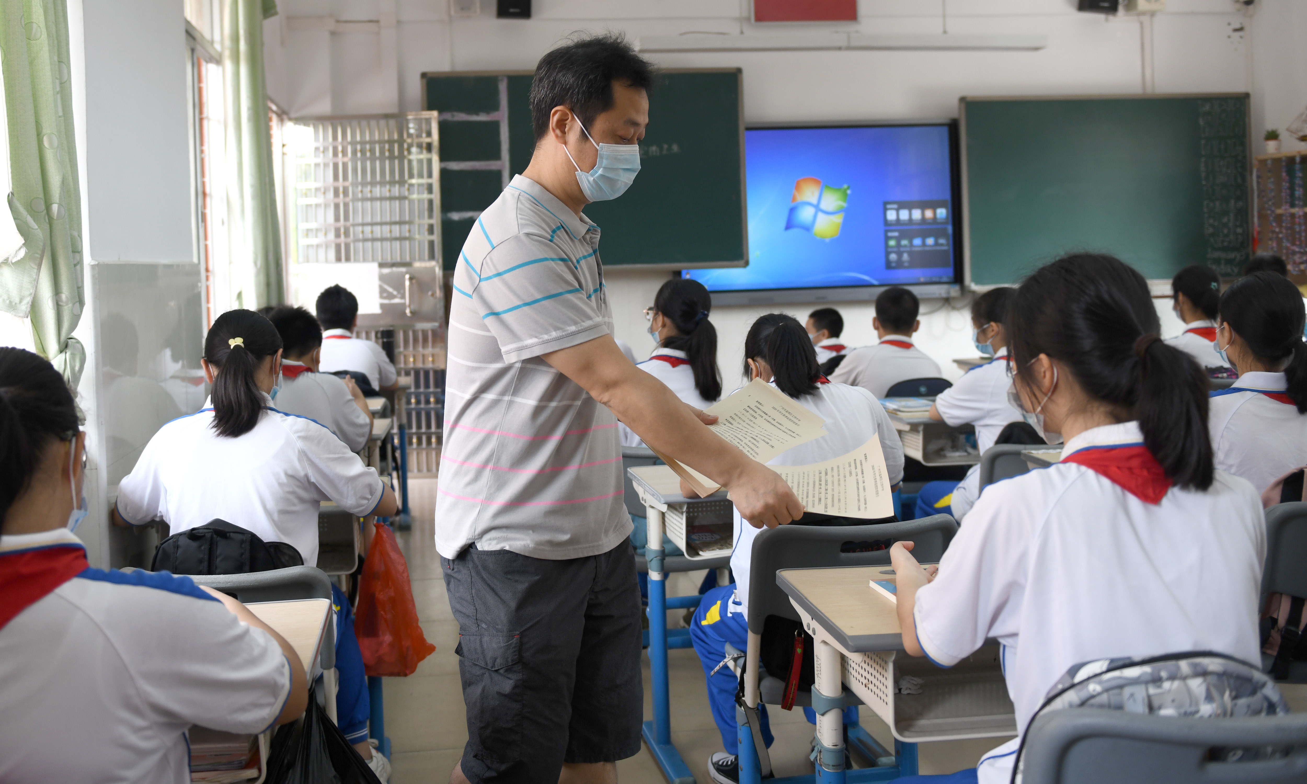 5月11日,广州市荔湾区文伟中学的老师在给初一学生发放返校防疫指引