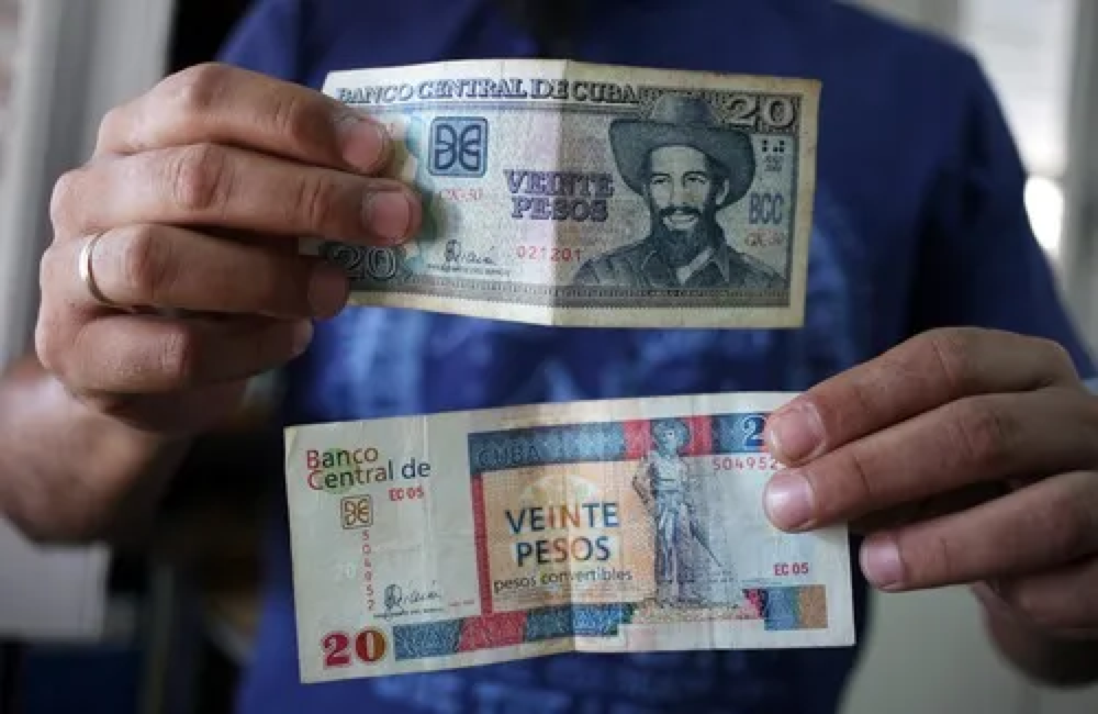 在古巴哈瓦那,一名男子展示两张20比索的纸币,一张为古巴比索(上),另