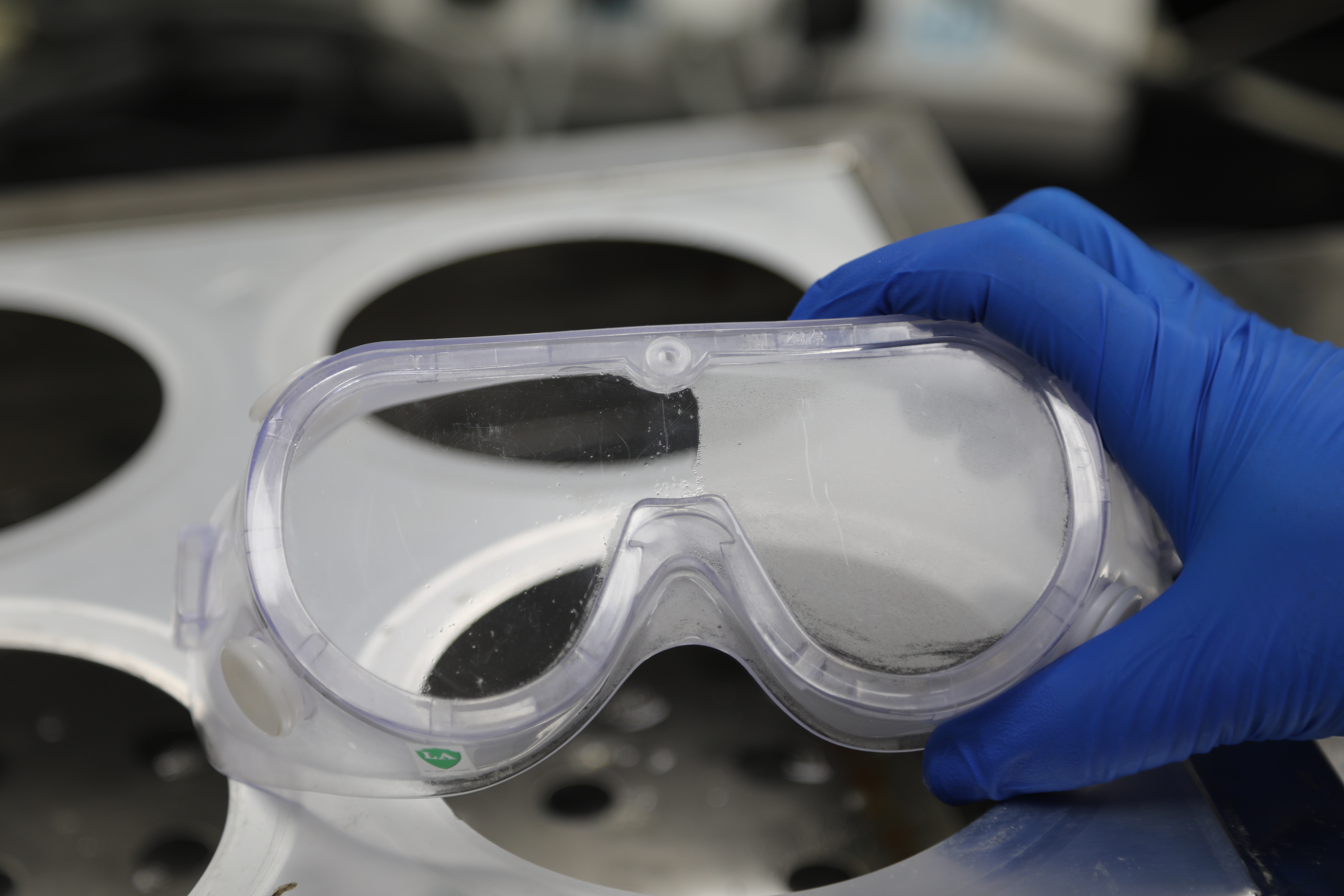 实验室工作人员向记者展示护目镜一侧涂抹了防雾喷雾液后的效果.